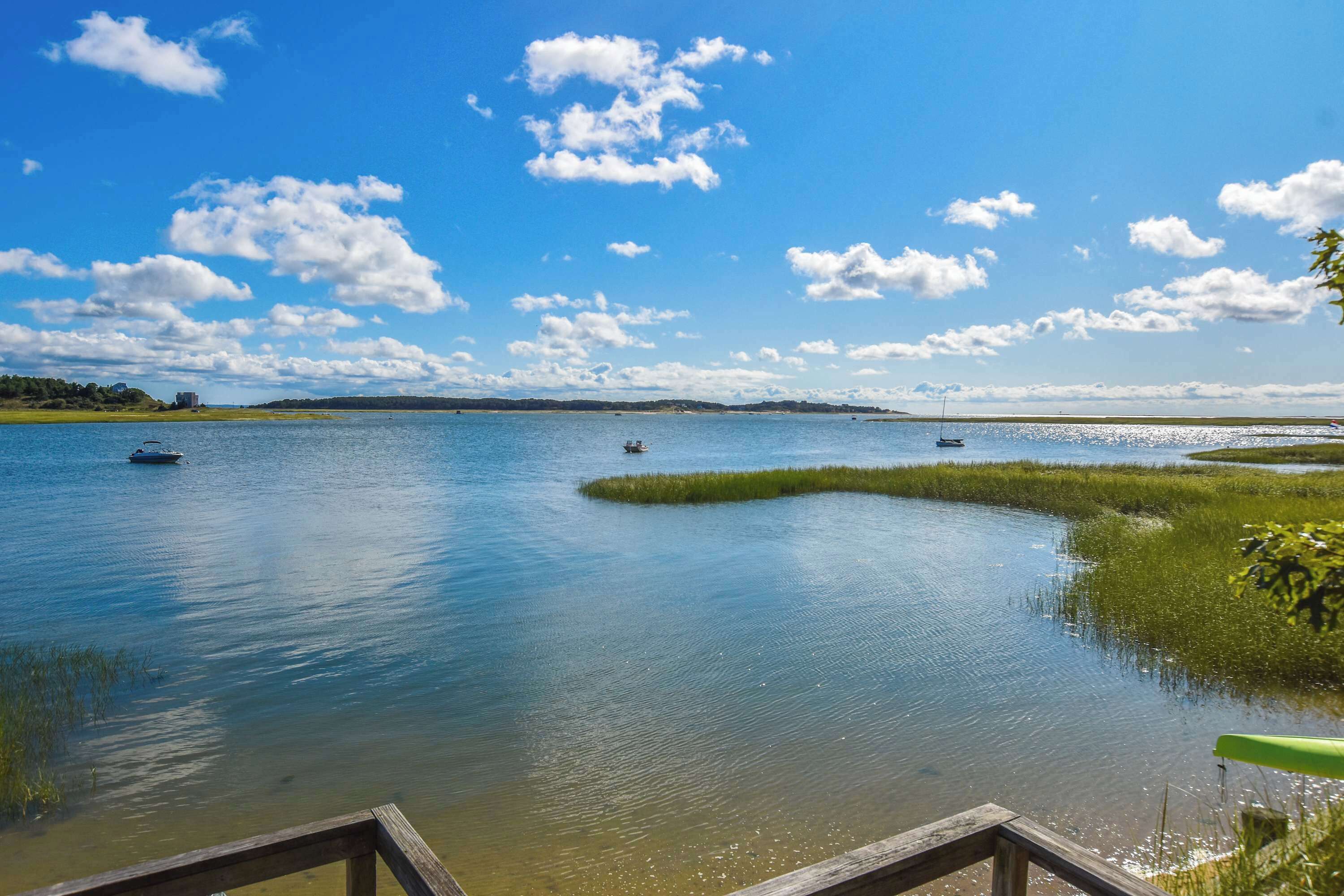 Ein ruhiger See mit Booten, saftigem Ufergrün und blauem Himmel.