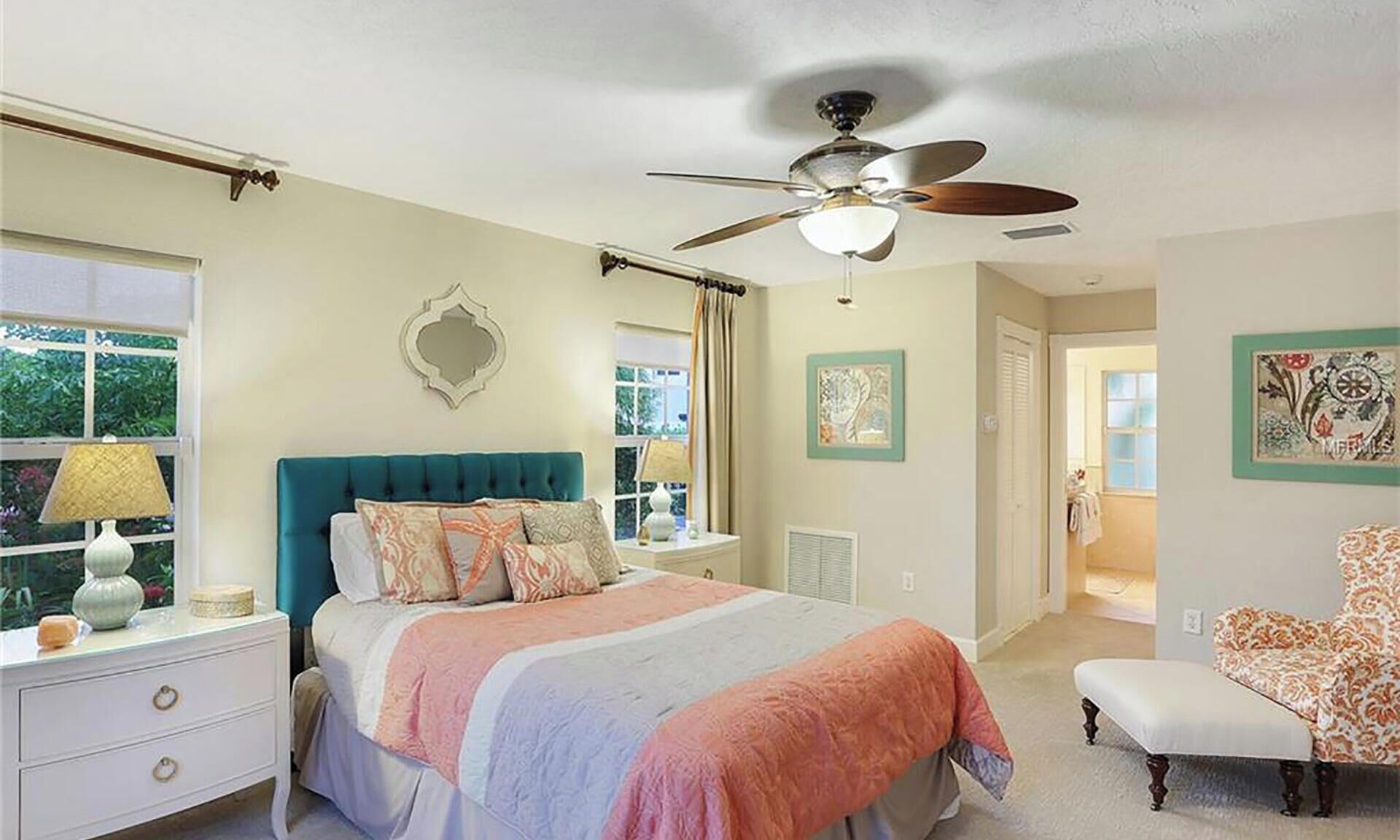 A bedroom with a bed, a ceiling fan, a window, and a chair.
