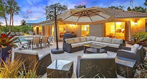 Un patio exterior con un amplio sofá modular, comedor y piscina.