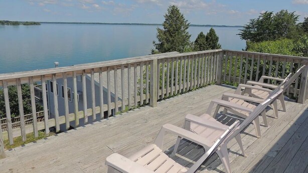 Une terrasse en bois avec des chaises longues donnant sur un lac paisible.