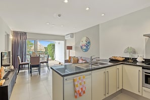 A modern kitchen with a central island, a dining area with a view, and a living space with a large window.