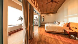 Un dormitorio amplio con una cama grande, suelo de madera y ventilador de techo.