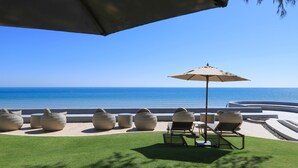 Un salón junto a la playa con asientos al aire libre y vistas al océano.