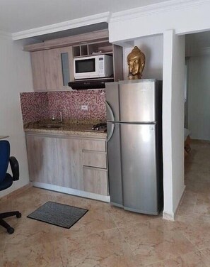 Compact kitchen with modern design, featuring a refrigerator, microwave, and cabinetry.