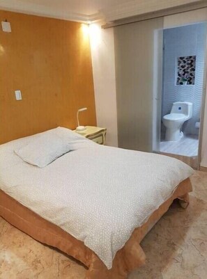 Cozy retreat with a single bed, bedside table, and en-suite bathroom featuring a toilet and sink.
