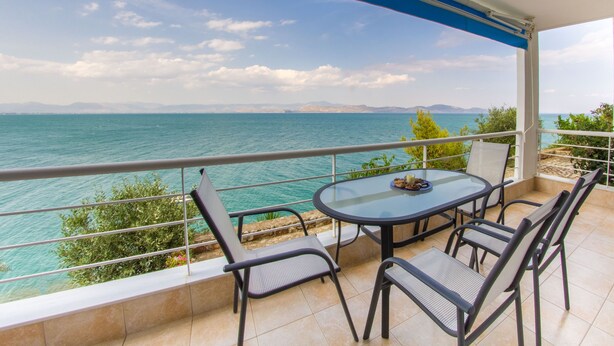 Een balkon met een tafel en stoelen, met uitzicht op een wateroppervlak.