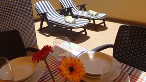 A terrace with two striped lounge chairs, a table with plates and a glass, and a flower arrangement. - Spacious, large terrace, sunny, WiFi, from the sea, 250 m. from the beach (Morro Jable)