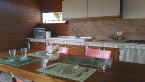 A wooden dining table with green placemats, clear glassware, and pink chairs. A small vase with white flowers is on the table. - Vite & Mare - Semi-detached house Le Solette Porto Palo - Belice Reserve (Marinella)