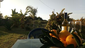 A table with a bottle of wine, two glasses, and oranges. - Vite & Mare - Semi-detached house Le Solette Porto Palo - Belice Reserve (Marinella)