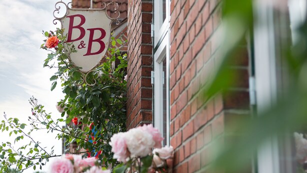 A building with a sign that reads "B&B" and a brick wall. - Charming, spacious town house, Friedrichstadt n. North Sea / 2-4 pers (Friedrichstadt)
