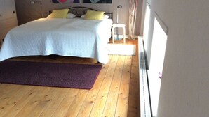 A bedroom with a bed, a nightstand, a lamp, and two posters on the wall. - Charming, spacious town house, Friedrichstadt n. North Sea / 2-4 pers (Friedrichstadt)