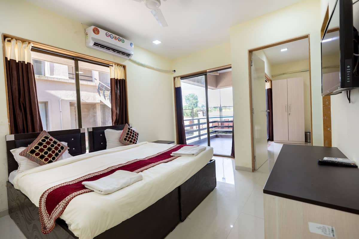 Quarto de hotel com cama, televisão, ar condicionado e varanda.