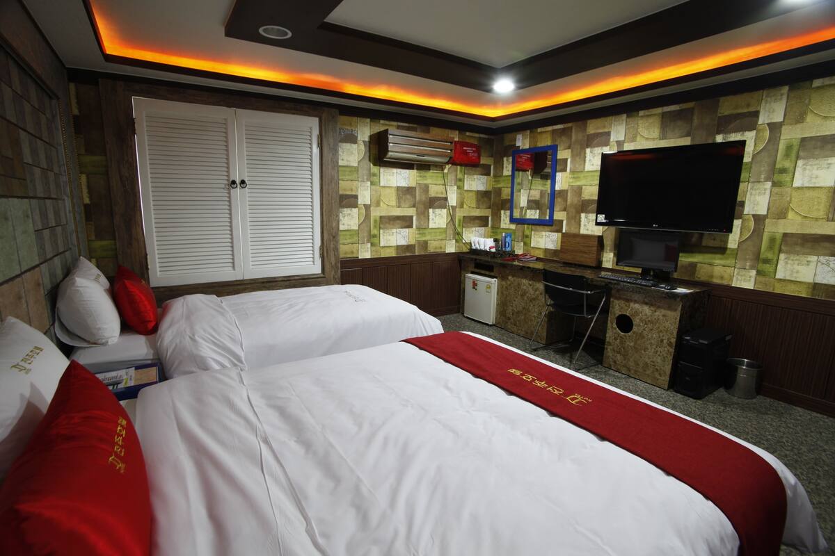 A hotel room with two beds, a desk, a television, and a minibar.