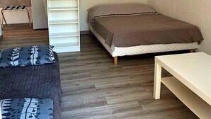 A compact bedroom with a bed, a small white desk, a chair, a wardrobe, and a radiator. - Quiet studio near Aubagne (La Penne-sur-Huveaune)