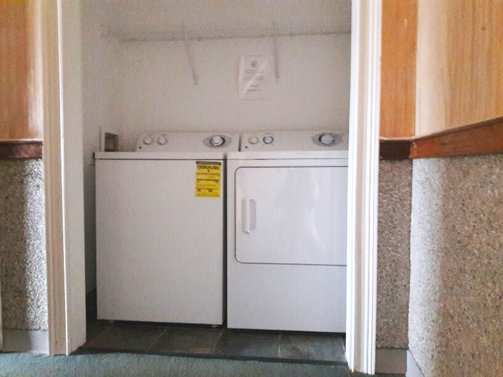 A laundry room with two white washing machines and a dryer.