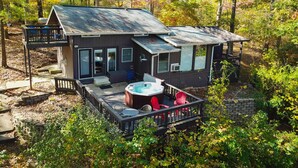 A cabin with a deck, hot tub, and outdoor seating.