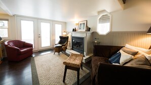 A living room with a fireplace, a red leather sofa, a brown sofa, and a wicker bench.