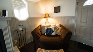 A cozy room with a brown sofa, a small round table, a lamp, and a window with a decorative frame.