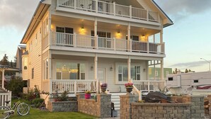 A multi-story building with balconies, a porch, and a bicycle parked outside. - The Lookout Lodge on Bishop's Beach with Spectacular views of Kachemak Bay! (Homer)