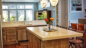 Un'ampia cucina con un'isola grande, mobili in legno e illuminazione a sospensione.