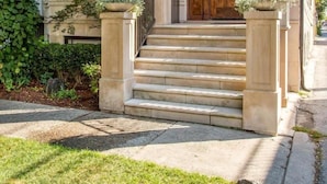 Una casa a due piani in mattoni con un portico, ampie finestre e una porta in legno.