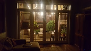 Una stanza con una porta a vetri scorrevoli che dà su un balcone con ringhiera in legno e piante in vaso.