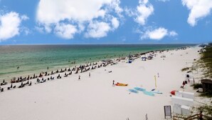 A beach with rows of umbrellas and beach chairs, a clear sky, and the ocean in the background. - Surfside 1501: Gulf Front Luxury Lookout (Miramar Beach)