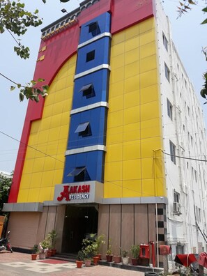 A multi-story building with a prominent yellow and red facade, featuring the name 'MAKASH RESIDENCY' on the ground floor.