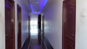 A hallway with wooden doors, a light-colored floor, and a ceiling with recessed lighting. - Hotel Aakash Residency (Madurai)