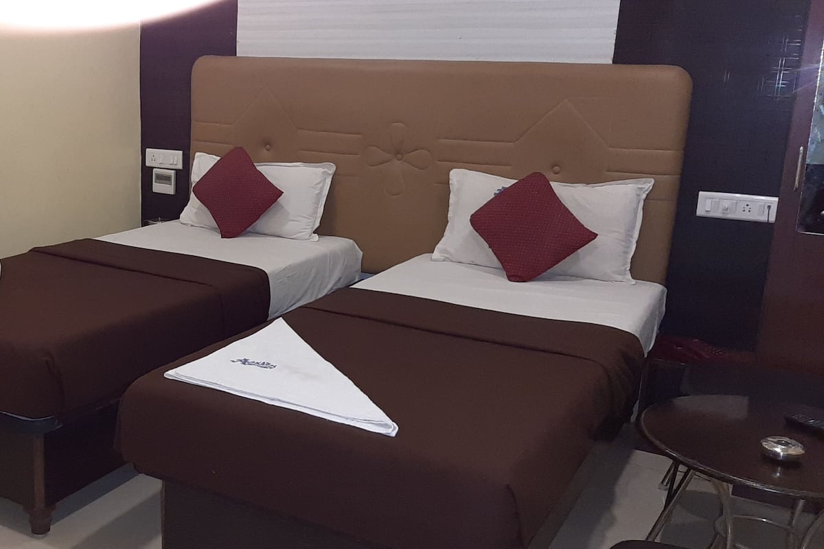 A hotel room with two single beds, each with a brown bedspread and a white pillow.