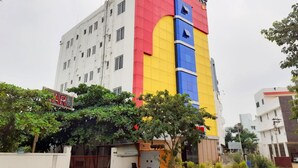 A multi-story building with a distinctive facade featuring a large, colorful logo. - Hotel Aakash Residency (Madurai)