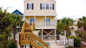 A two-story house with a balcony and a wooden staircase leading to the entrance. - EXTREME OCEANFRONT -  Heated Pool & Hot Tub / Linens & Gas grill inc. discounted (Surfside Beach)
