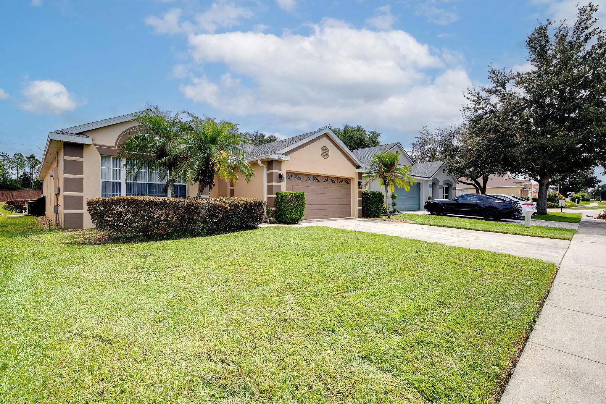 A residential house with a well-maintained lawn, a garage, and a parked car.