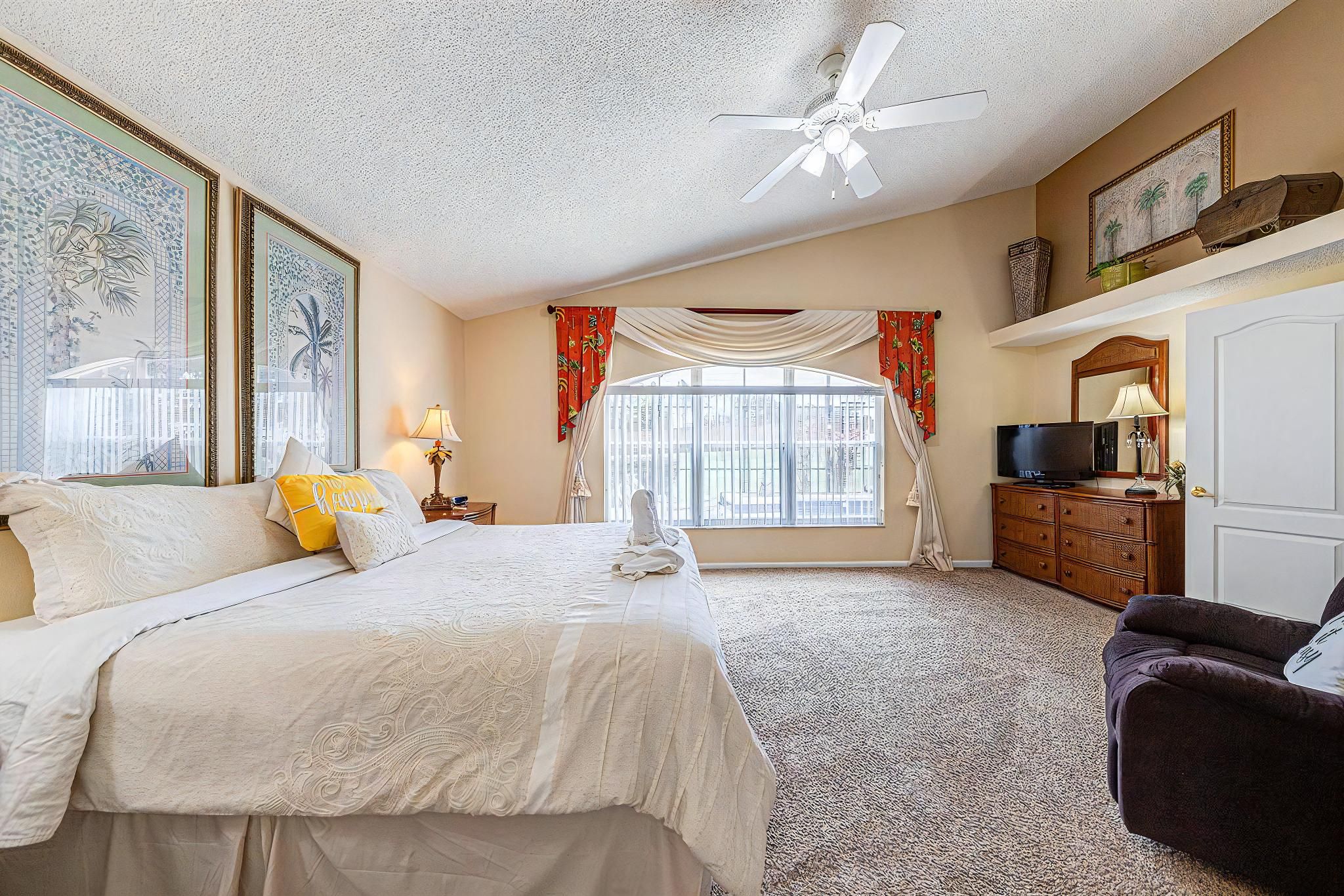 A hotel room with a bed, a television, a desk, and a chair.