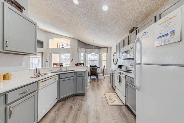 A modern kitchen with grey cabinetry, a central island, and a dining area with a view.