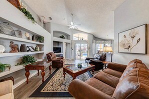 A spacious living room with leather sofas, a glass coffee table, and decorative shelves.
