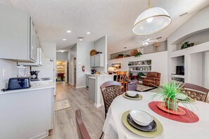 A modern kitchen with a dining area, a visible fire extinguisher, and a ceiling fan.