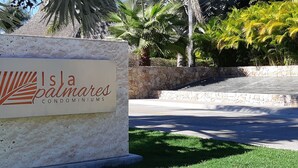 A sign for Isla Palmas Condominiums with a stone wall and palm trees in the background. - Executive 2 bed, 2 bath, Penthouse, Paradise Village, el Tigre, Isla Palmares (Nuevo Vallarta)