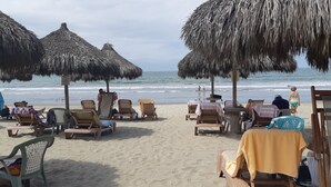 A beach with thatched umbrellas and lounge chairs. - Executive 2 bed, 2 bath, Penthouse, Paradise Village, el Tigre, Isla Palmares (Nuevo Vallarta)
