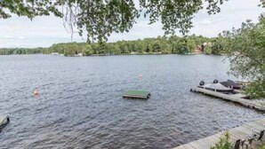 A lakeside view with a dock, a floating platform, and a wooden deck with chairs. - Perfect Cabin on Lake Minocqua! (Minocqua)