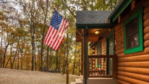 Une cabane en bois avec une véranda et un drapeau.