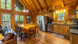 L’intérieur d’un chalet en bois comprend un coin repas, une cuisine et un salon avec un canapé en cuir.