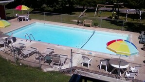 A rectangular swimming pool with a diving board and multiple lounge chairs and umbrellas around it. - 2nd floor Poolside Studio with kitchenette. (Branson)