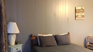 A bedroom with a bed, a nightstand with a lamp, a wall-mounted sign with motivational phrases, and a chair. - 2nd floor Poolside Studio with kitchenette. (Branson)