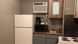 A compact kitchen with a refrigerator, microwave, stove, and a coffee maker. - 2nd floor Poolside Studio with kitchenette. (Branson)