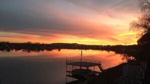 A calm lake at sunset with a dock and a fence in the foreground. - Kathleen Suite at the Captains House (Granbury)