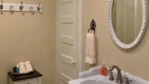 A bathroom with a white sink, a mirror, a towel rack, and a chandelier. - Kathleen Suite at the Captains House (Granbury)