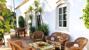 An outdoor patio with wicker furniture, a glass-top table, and potted plants. - Beautiful Restored Algarve Typical Farmhouse, with Private Pool and Sea Views (Loule)