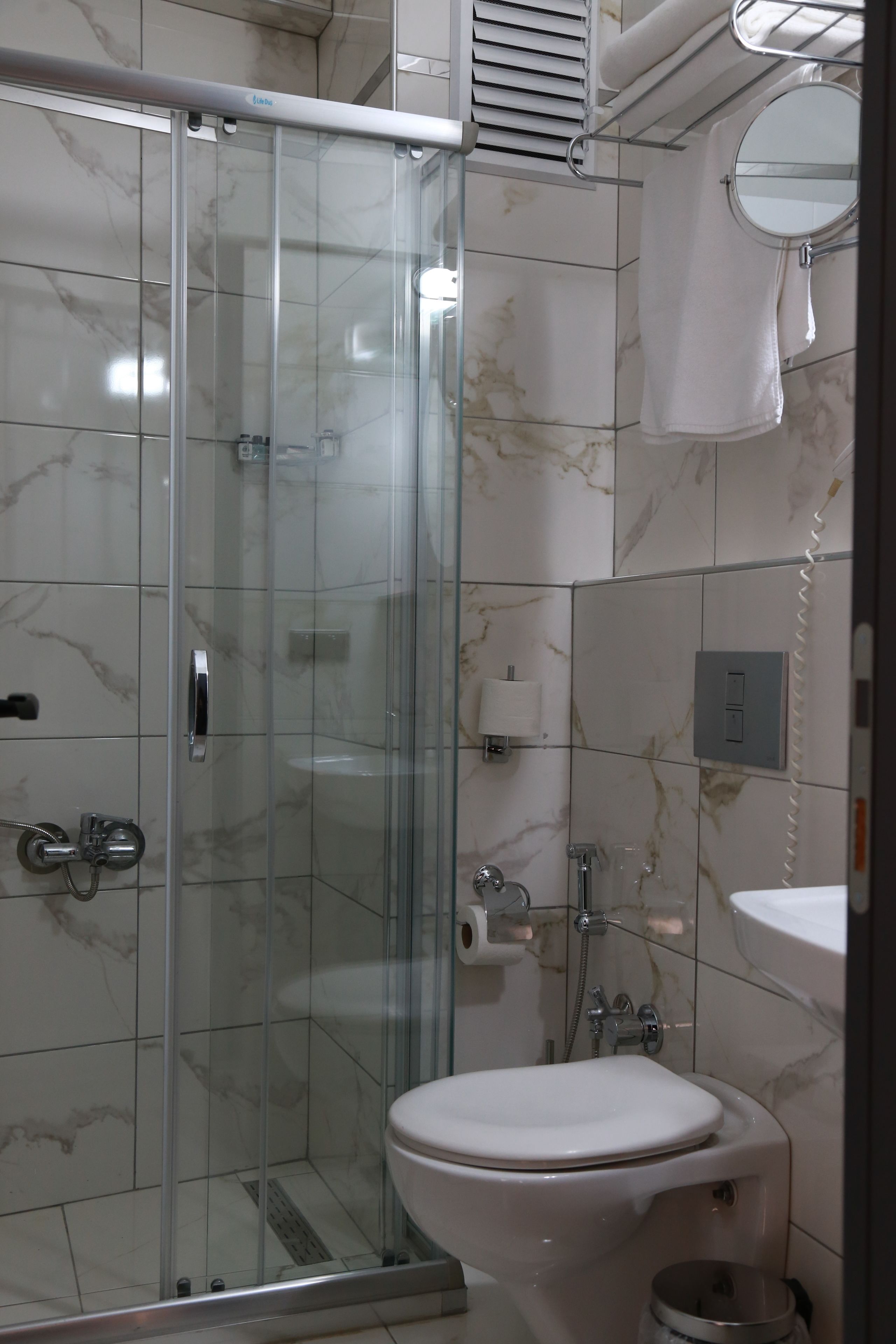 A bathroom with a glass-enclosed shower, a toilet, and a sink.