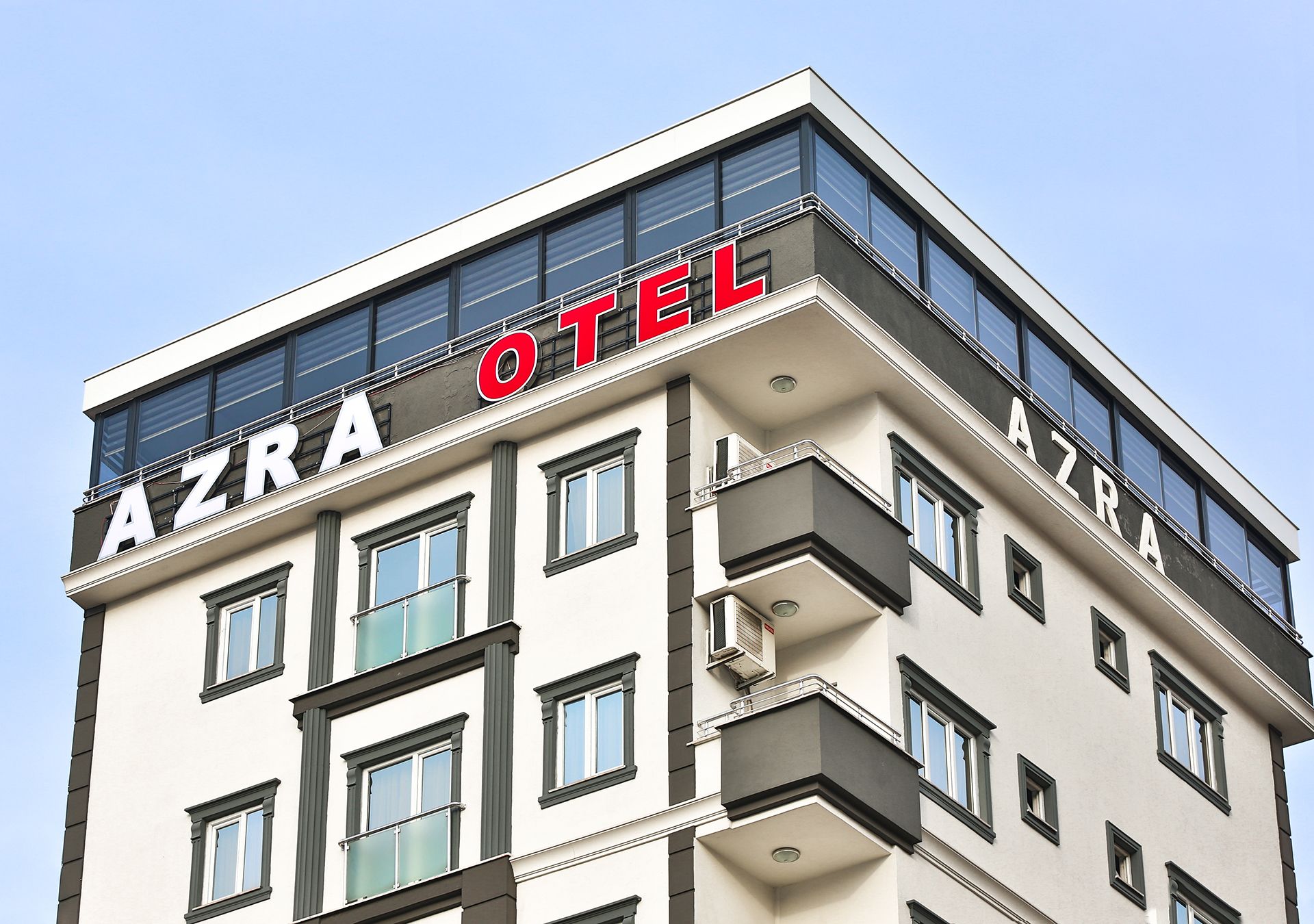 En byggnad med flera våningar, där namnet ”AZRA HOTEL” är tydligt synligt på fasaden.
